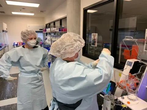 School of Pharmacy researchers wearing protective equipment work together in a laboratory.