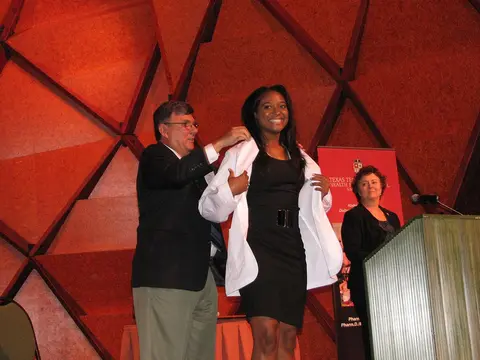 Pharmacy student receives her white coat during a ceremony.