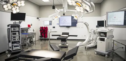 Medical simulation laboratory equipped with clinical training mannequins and monitoring equipment.