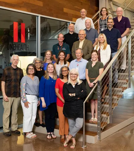 Group photo of faculty and staff gathered on and around a staircase inside the ONEHEALTH facility.