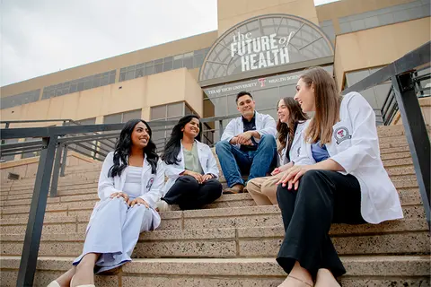 Medical students gather on the steps outside a TTUHSC building.