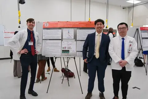 Three researchers standing beside a scientific research poster during a TTUHSC poster presentation.