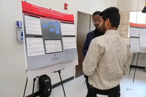 Two researchers discussing a scientific research poster during a TTUHSC poster presentation.