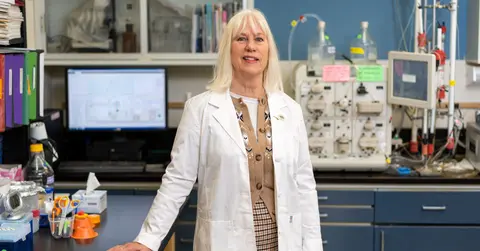 Gail Cornwall, Ph.D., stands in her laboratory beside research equipment.