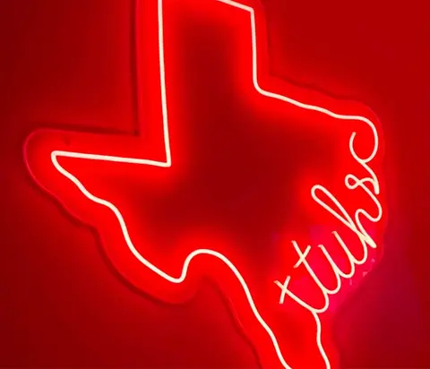 Red neon sign shaped like Texas with “TTUHSC” written inside.