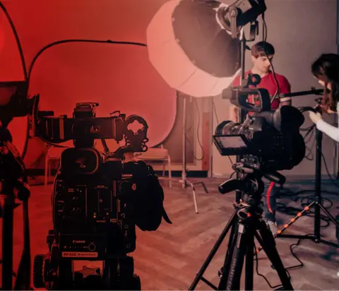 Video production set with professional cameras, lighting equipment and crew members.