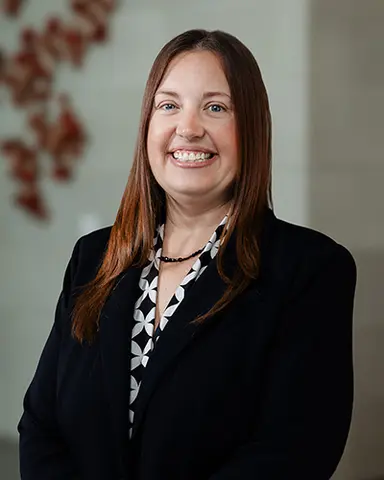 Headshot of Kelly Moseley wearing a black blazer over a black-and-white pattern top, smiling at the camera.