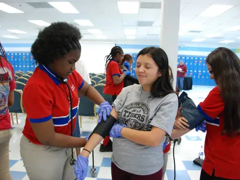 Students practice taking blood pressure during a hands-on healthcare activity.