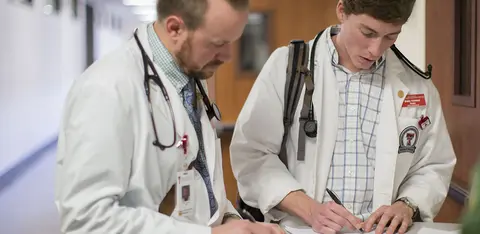 Physician and medical student review notes during clinical training.