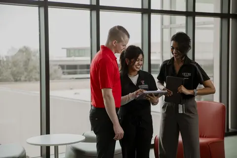 Three TTUHSC Student Government Association members reviewing information together on tablets.