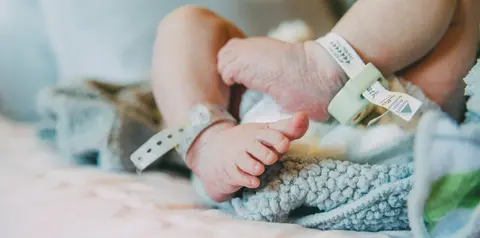Newborn’s feet wearing hospital identification bands.
