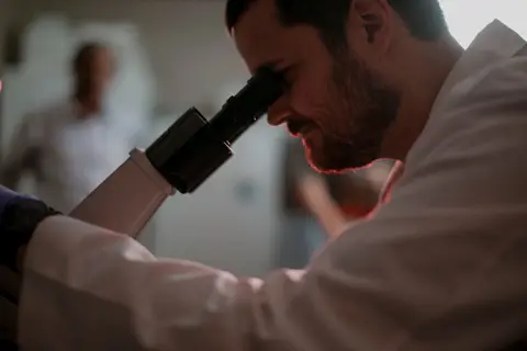 Researcher examining a sample through a microscope in a laboratory.