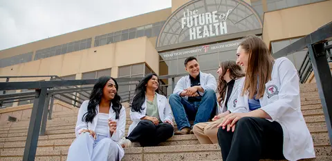 White coat students visiting on the stairs outside of TTUHSC Lubbock Campus.