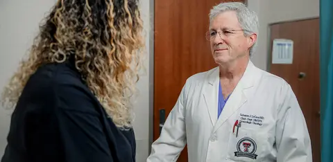 Doctor greeting patient at the door of the medical practice, shaking their hand.
