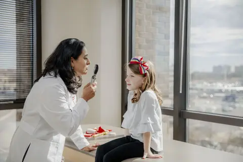 A neurologist conducting a medical test on a child in a hospital.