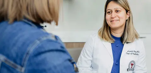 Doctor smiling at a patient in a medical exam room.