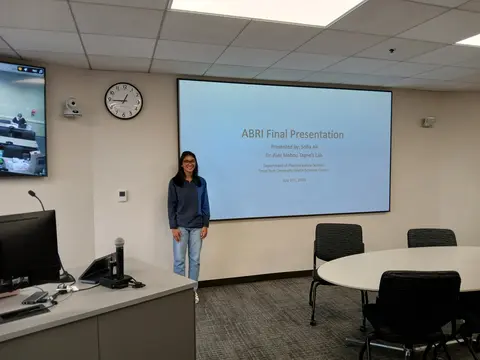 TTUHSC Daily Dose Summer Research Internship Ali next to presentation