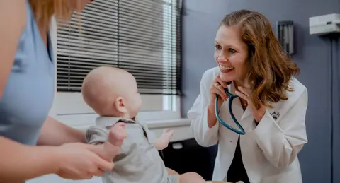 Doctor performing an examination on a young patient in a medical exam room.