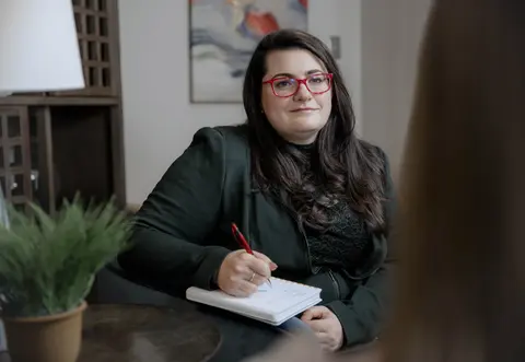 Mental health professional holding a notebook during a counseling session.