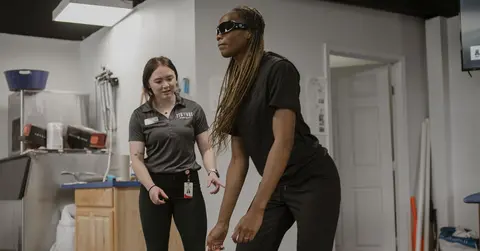 athletic trainer helping an athlete with exercises 