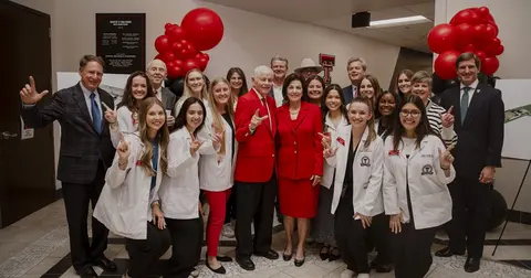 group photo of people in white coats holding up 