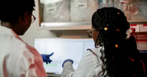 two experts look at a computer screen in a lab