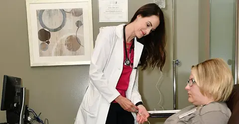 Doctor standing and patient on a chair at the Texas Tech Physicians Headache clinic