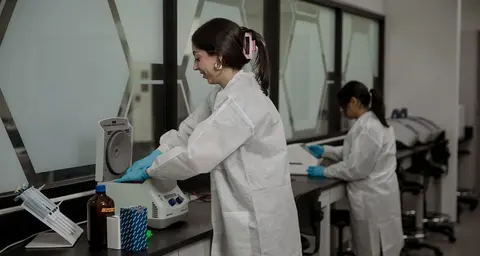 womann in scrubs and gloves working with DNA equipment in a lab