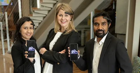 three people stand holding pieces of technology