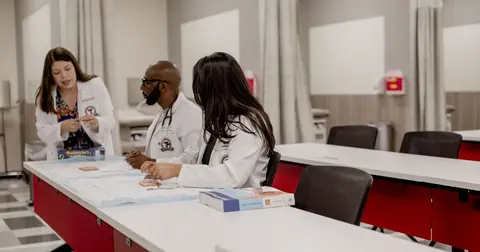 three health care professionals sit at the end of a long table