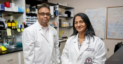 two scientists in lap coats standing side by side