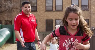 man happily chasing his daughter outside