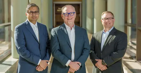 three men smiling, standing in a hallway at TTUHSC