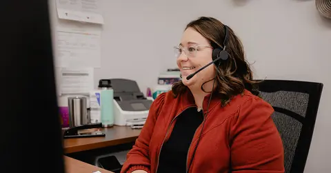 woman working at a computer with a remote headset