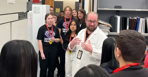 Pharmacy professor talks to a group of high school students.