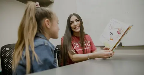 woman reading a book to a young girl