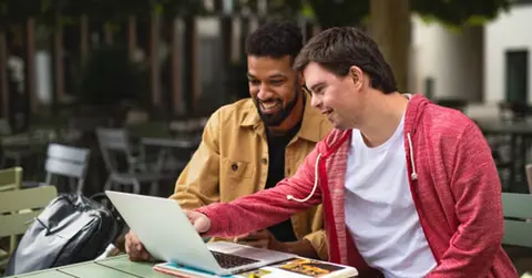 two people look at a laptop together