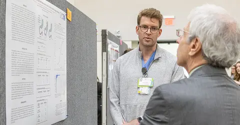 student giving poster presentation to Dean Berk 