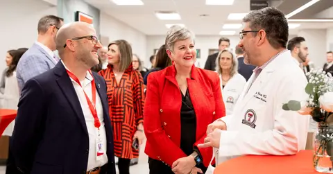 Three people talk around a cocktail table at an open house event.