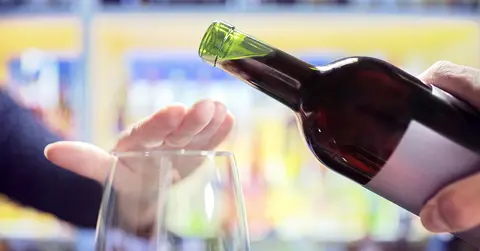 hand preventing wine from being poured