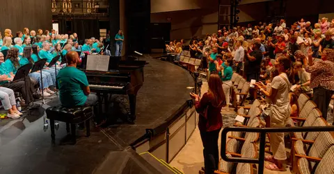Audience cheers for performers on stage at a concert.