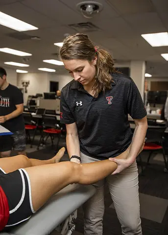 athletic trainer looking at athlete's leg