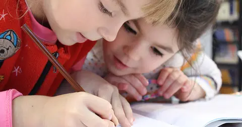 two children reading a workbook