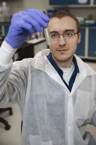 Man in labcoat looking at vile