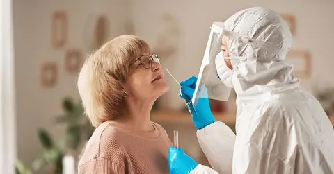woman recieving a COVID-19 test from a health care professional in lab gear