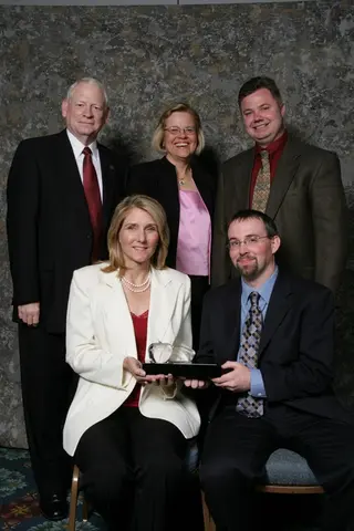 group of colleagues posing for a photo with a grey backdrop