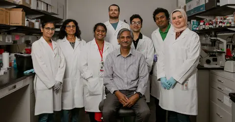 Several TTUHSC researchers wear white coats and stand in their lab.