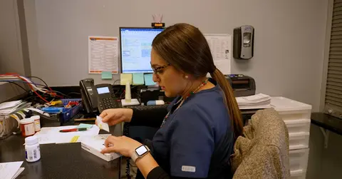 woman working at a desk looking at notes