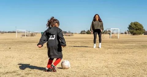 mother and daughter playing soccer on a field