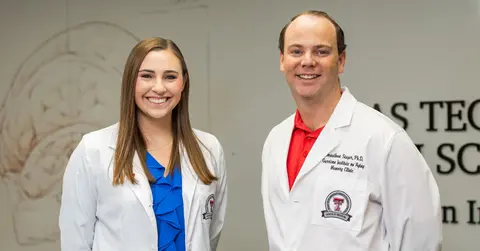 TWoman and man stand together wearing white coats.